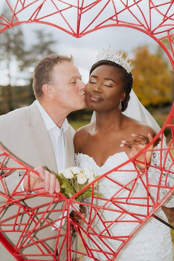 Couple de mariés dans une sculpture en cœur rouge